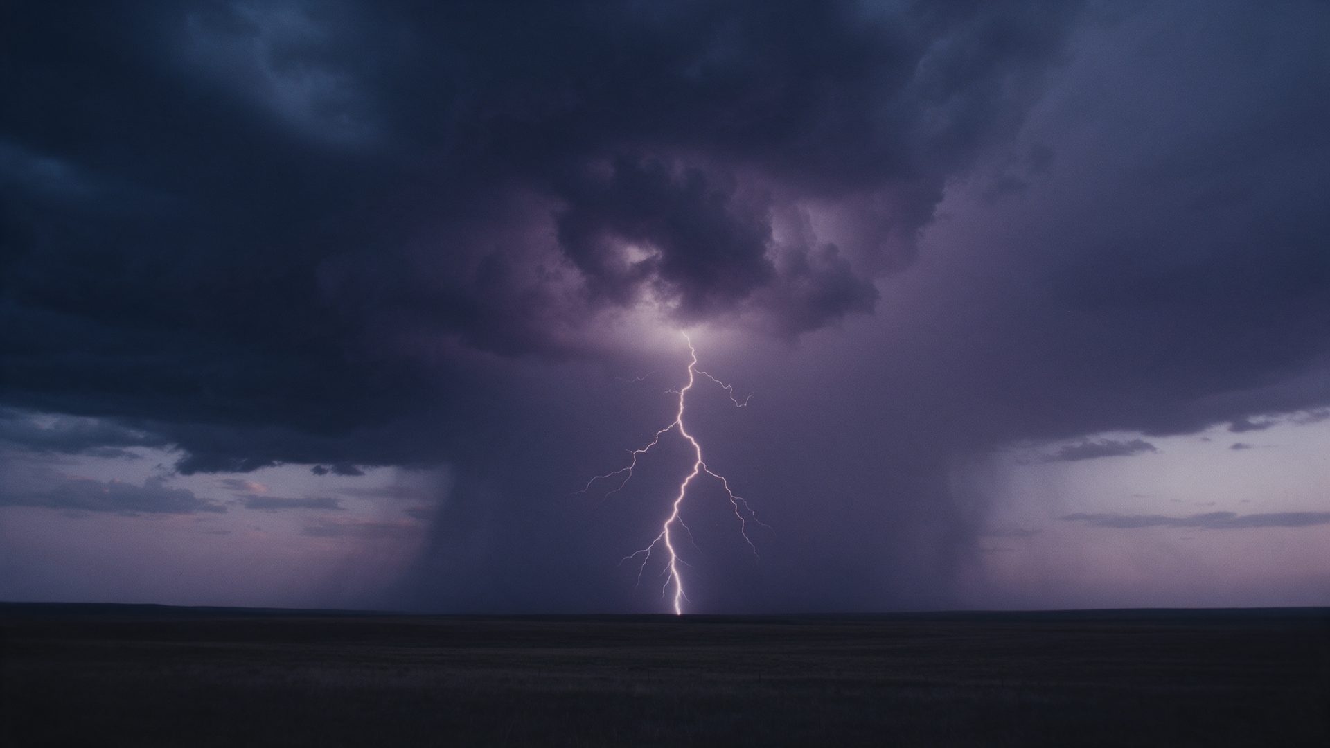 A single lightning bolt falling from a violet storm cloud over a flat plain at dusk.
